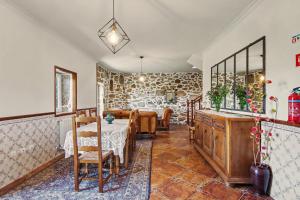a dining room with a table and chairs and a stone wall at Casa Na Aldeia in Arões