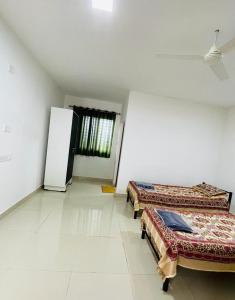 a room with two beds and a refrigerator in it at Vaidic Yoga Retreat in Ponsuli