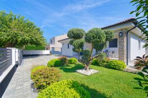 a garden in front of a house with a tree at Villa Tea by Rent Istria in Umag
