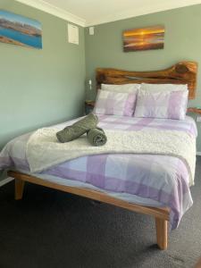 a bedroom with a large bed with purple and white sheets at Robbies Hut in Greymouth +5 photos