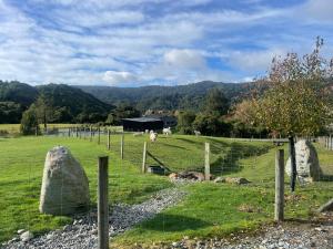 a farm with sheep in a field with a fence at Robbies Hut in Greymouth
