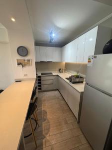 a kitchen with white cabinets and a clock on the ceiling at Bello departamento av del mar in Coquimbo +8 photos