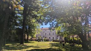 a large white house with trees in the foreground at L'héritage in Champdeniers