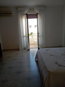 a bedroom with a bed and a door to a balcony at Una Terrazza sul mare in San Ferdinando