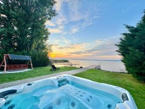 a hot tub in a yard with a view of the water at Zöldpart Villa in Balatonszárszó