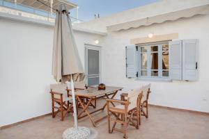 a patio with a table and chairs and an umbrella at Consolato House in Patmos