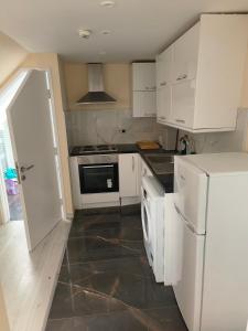 a kitchen with white cabinets and a black floor at Yunus in Croydon