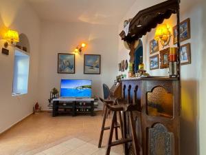 a living room with a tv and a desk with a computer at Cycladic House with Aegean Sea View in Aegiali