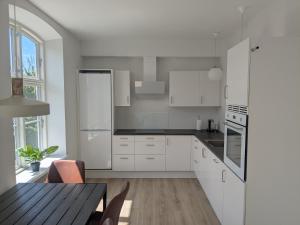 a kitchen with white cabinets and a wooden table at Stubbekøbing Square View Stopover in Stubbekøbing