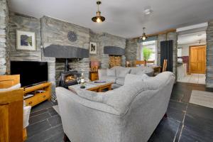 a living room with couches and a tv and a stone wall at Finest Retreats - Garreg Ddu in Blaenau-Ffestiniog