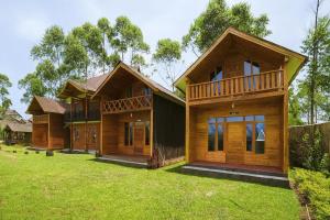a row of wooden houses on a lawn at Cozzy Villa TB & Outbond in Riunggunung