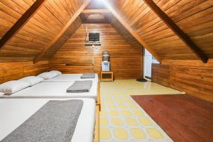 a room with two beds in a wooden room at Cozzy Villa TB & Outbond in Riunggunung