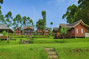 a group of houses in a field of grass at Cozzy Villa TB & Outbond in Riunggunung