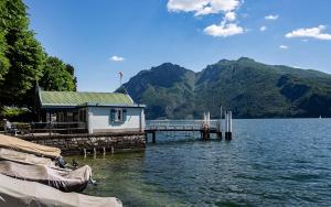 a house on a dock on a lake with mountains at Lake Como with view, sauna and air conditioning in Mandello del Lario