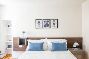 a white bedroom with a bed with blue pillows at Lake Como with view, sauna and air conditioning in Mandello del Lario