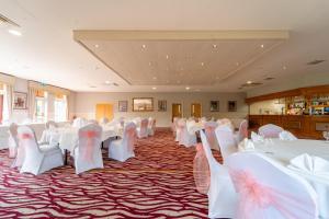 a banquet hall with white tables and white chairs at Bagden Hall Hotel in Scissett