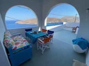 a room with two windows and a table and chairs at Cycladic House with Aegean Sea View in Aegiali