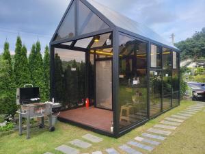 a black house with a deck in the grass at Sarah's Small Garden in Cheonan
