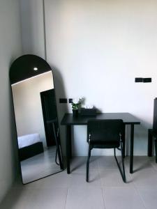 a table and chair in a room with a mirror at Atrium Kathu Hotel in Ban Kathu (1)