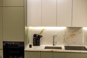 a kitchen with a sink and white cabinets at Dream Luxury Suite in Tirana +35 photos