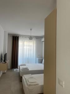 a bedroom with two beds and a tv in it at f & xh apartaments in Kavajë