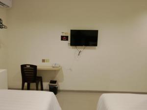 a room with two beds and a desk and a television at Priority Teuku Umar Samarinda in Loa Bakong
