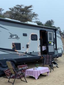 a camper with a table and chairs in front of it at كرفان نور القمر in Al Namas