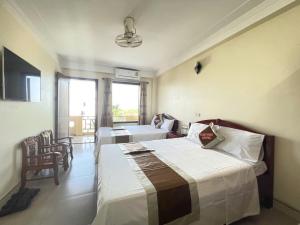 a hotel room with two beds and a television at Huệ Vinh Hotel in Cửa Lô