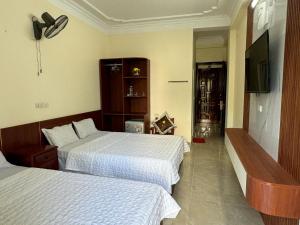 a hotel room with two beds and a flat screen tv at Huệ Vinh Hotel in Cửa Lô