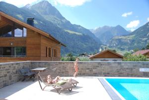 dwie osoby siedzą na krzesłach obok basenu w obiekcie EdelWeiss AlpinLodge w mieście Matrei in Osttirol