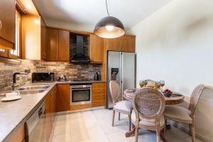 a kitchen with wooden cabinets and a table with chairs at Mythodea Luxury Villa Ι Sunset Horizon & Jacuzzi in Naxos Chora