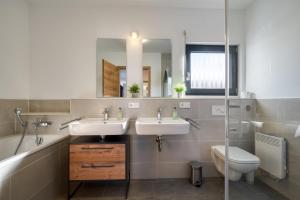 a bathroom with two sinks and a toilet and a mirror at Mountain Chalet Top 3- mit Garten und Grill in Fieberbrunn +11 photos