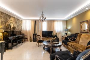 a living room with a couch and a table and a piano at Mythodea Luxury Villa Ι Sunset Horizon & Jacuzzi in Naxos Chora