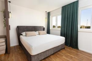 a bedroom with a bed and two windows at Apartmani Ivano & Anđelo in Međugorje