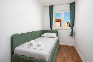 a green bed in a room with a window at Apartmani Ivano & Anđelo in Međugorje