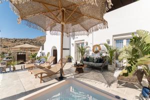 an outdoor patio with a pool and an umbrella at Mythodea Luxury Villa Ι Sunset Horizon & Jacuzzi in Naxos Chora