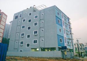 a large gray building with blue at NRI Hotels & Coliving in Hyderabad