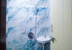 a blue and white bathroom with a sink and a shower at NRI Hotels & Coliving in Hyderabad