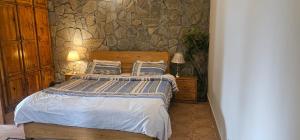 a bedroom with a bed and a stone wall at Green's Cottage in Nathia Gali