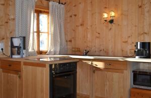 a kitchen with wooden cabinets and a sink and a stove at Urgemütliche Lennkhütte in Rauris +7 photos