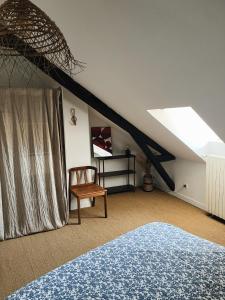 a attic room with a bed and a chair at Le Haut des Halles in Martel