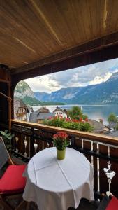 a table on a balcony with a view of the water at Café Pension Leopoldine in Hallstatt