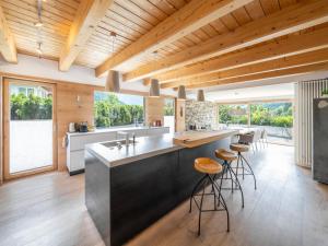 a kitchen with wooden ceilings and a large island with bar stools at Chalet Sendlhofer in Bad Hofgastein