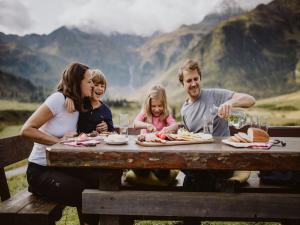 a family sitting at a picnic table eating food at Chalet Sendlhofer in Bad Hofgastein