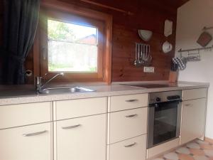 a kitchen with white cabinets and a sink and a window at Blockhaus Hipp in Steingaden