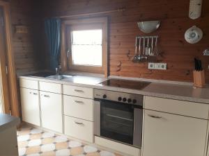 a kitchen with white cabinets and a stove and a window at Blockhaus Hipp in Steingaden