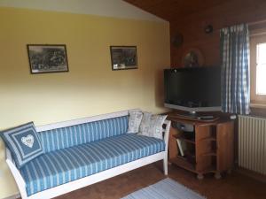 a living room with a blue couch and a flat screen tv at Blockhaus Hipp in Steingaden +18 photos