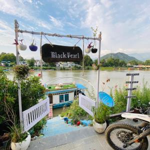 a sign that reads black pearl with a boat on a river at Blackpearl in Srinagar