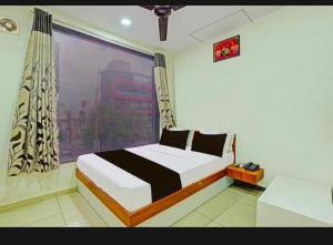 a bedroom with a bed and a large window at Hotel Kalyan in Rajkot