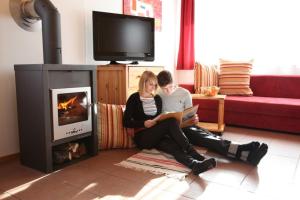 a man and woman reading a book in front of a fireplace at Hüttendorf Präbichl 1 in Vordernberg +5 photos
